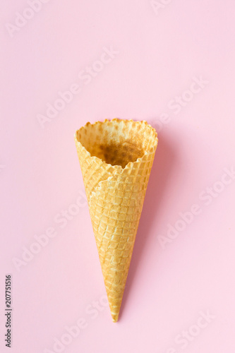 Flat-lay of waffle sweet cone over pastel light pink background, top view.