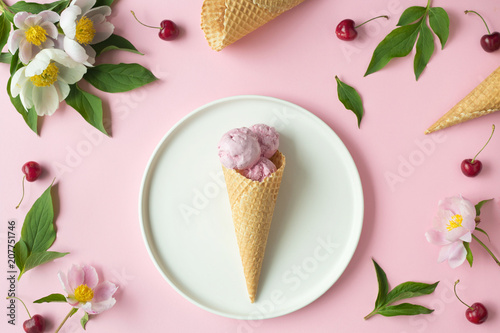Flatlay of pink ice cream scoops, cerry, sweet cones and peonies over pastel pink background. Top view with space for your text