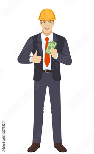 Businessman in construction helmet showing thumb up with cash money