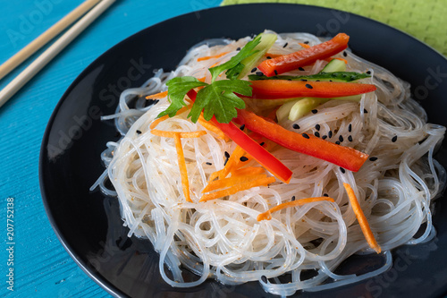 cellophane noodles on a plate on a wooden table with vegetable sauce and dressing photo