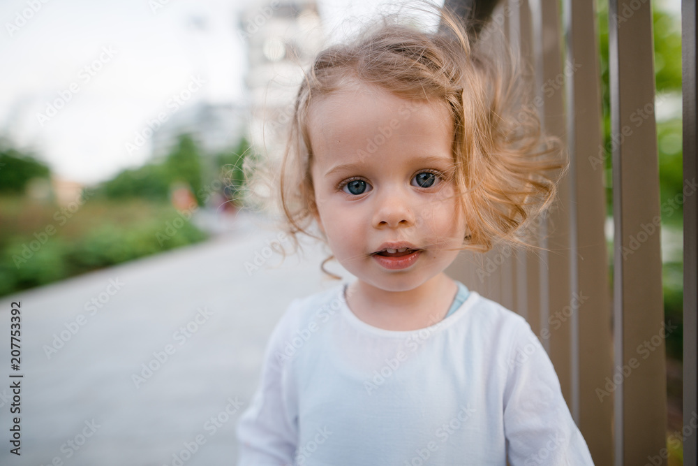 Close up portrait of beautiful cute little girl with curly blonde hair,  blue eyes wearing white dress looking at the camera. Outdoors in the park  Stock Photo | Adobe Stock