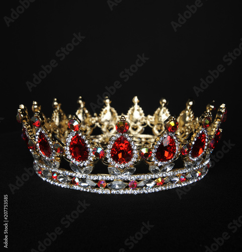 portrait of a beautiful jewelled ruby, diamond and golden crown, photographed on a black studio background.