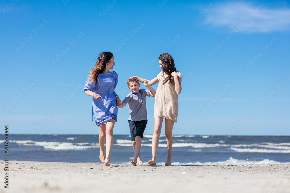 Mother and her children having a walk by the sea.