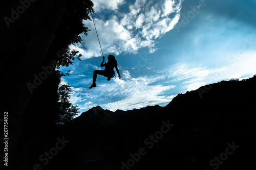 Silhouette of a girl coming down from the rope after climbing