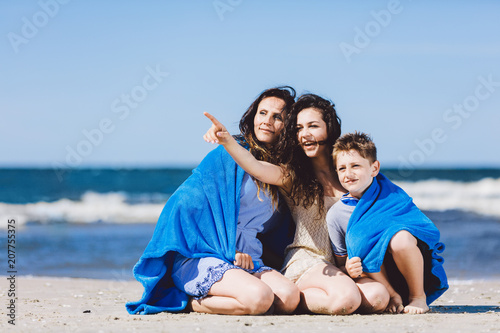 Family sitting on a beach, older sister pointing her finger
