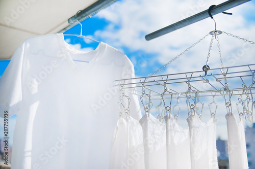 晴れた日に白いタオルとTシャツを洗濯して干す様子。 