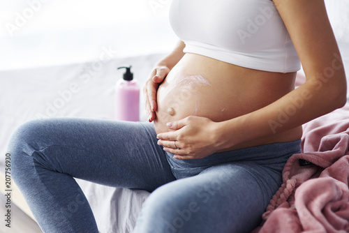 Close up of pregnant women applying moisturizer