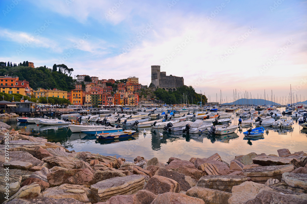 colorful boats and seascape with old castle and blue cloudy sky with sunset  in Lerici in Liguria, Italy