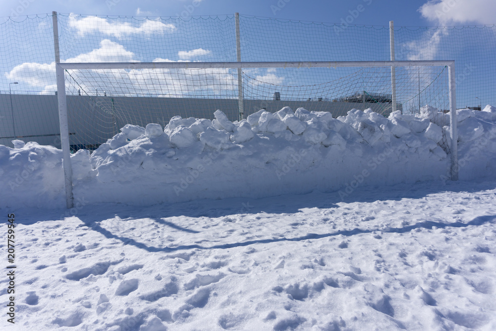 football goal littered with snow winter field .