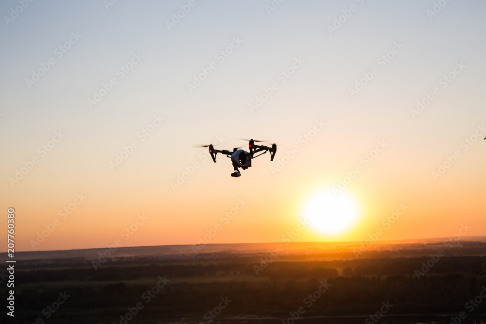 silhouette of drone, quadrocopter with photo camera flying in the sky. silhouette of drone, quadrocopter with photo camera flying in the sky.