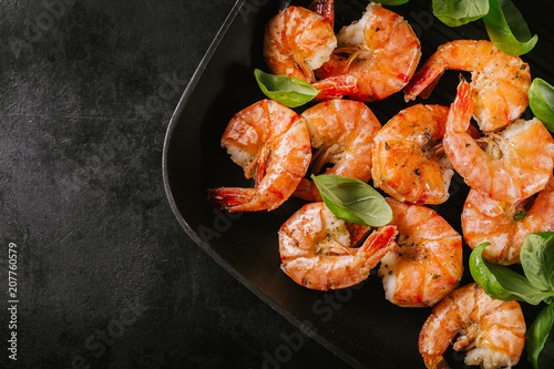 Grilled king prawns on pan on dark table
