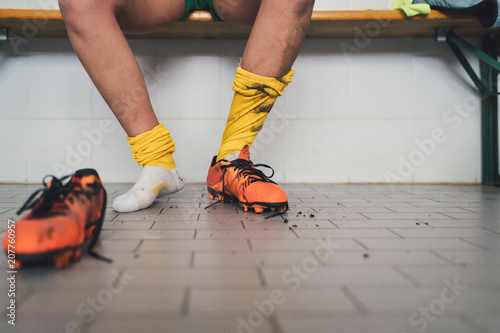 Football player in one football boot in changing room