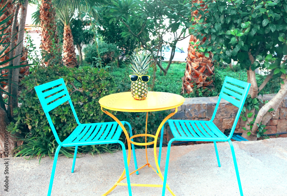 Fashion pineapple in a sunglasses on the table outdoors, summer holidays, vacation and food concept Fashion pineapple in a sunglasses on the table outdoors, summer holidays, vacation and food concept