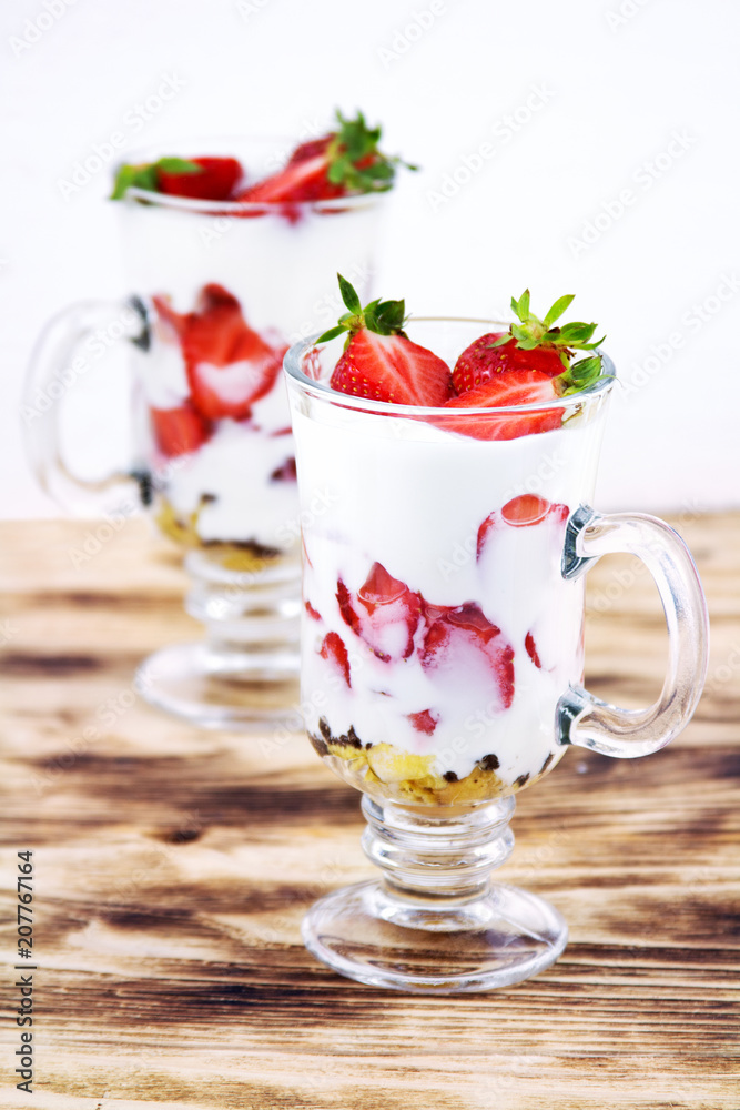 Tasty sweet dessert with yogurt and fresh strawberry on a rustic table on a white background Tasty sweet dessert with yogurt and fresh strawberry on a rustic table on a white background