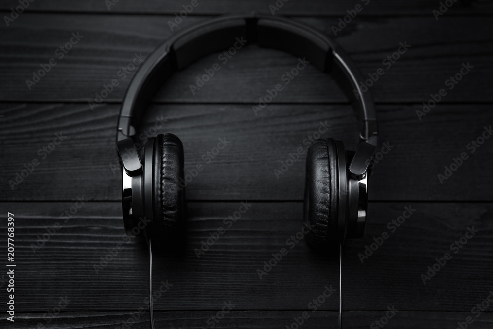 Black headphones on black wooden dark background. Black headphones on black wooden dark background.
