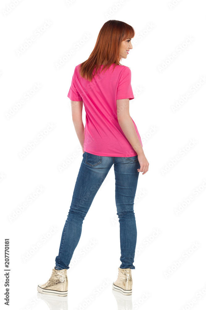 Rear View Of Smiling Young Woman In Pink Shirt And Gold Sneakers Rear View Of Smiling Young Woman In Pink Shirt And Gold Sneakers