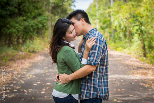 Fotografía Young man kiss young woman on a forest road.