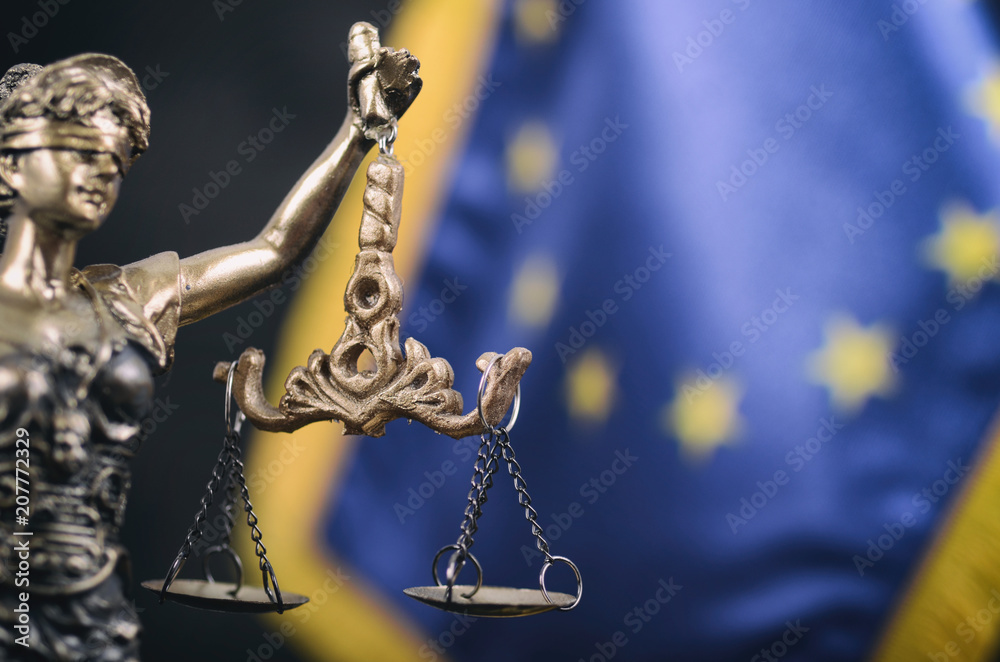 Scales of Justice, Justitia, Lady Justice in front of the European Union flag in the background. Scales of Justice, Justitia, Lady Justice in front of the European Union flag in the background.
