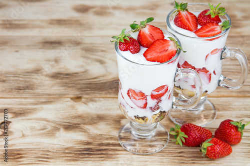 Tasty sweet dessert with yogurt and fresh strawberry on a rustic background