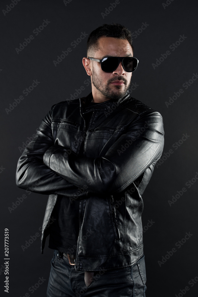 Plakat Confident man stand with arms folded. Bearded man in trendy sunglasses. Fashion model in leather jacket and jeans. Fashion and style. Confidence with sexuality and charisma