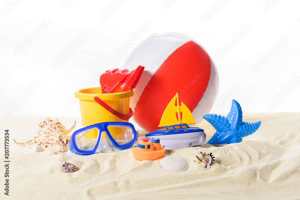 Beach ball and toys in sand isolated on white Beach ball and toys in sand isolated on white