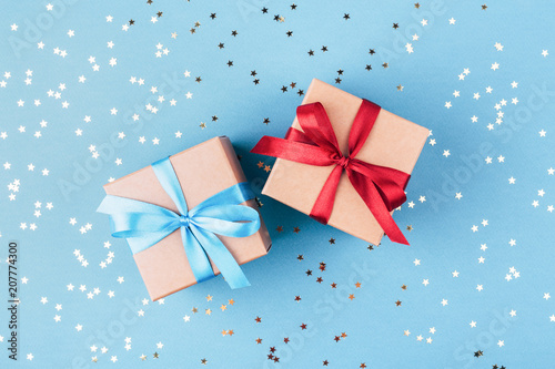 Two gift boxes wrapped in kraft paper and tied with ribbon on blue background...