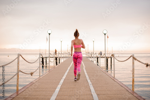 Back view of beautiful slim and young girl running over the wooden bridge © fesenko