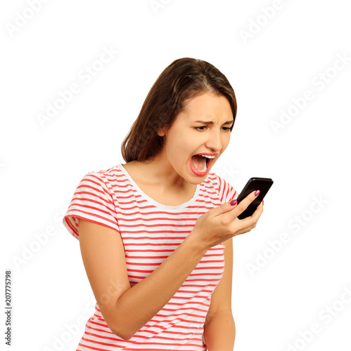 Annoyed hysterical young woman screams into mobile phone, the girl is displeased with the conversation. emotional girl isolated on white background