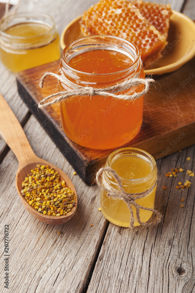 Golden honeycombs and honey jars on wooden table Golden honeycombs and honey jars on wooden table