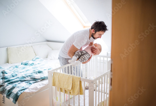 Bilde på lerret Father putting a sleeping toddler girl into cot at home.