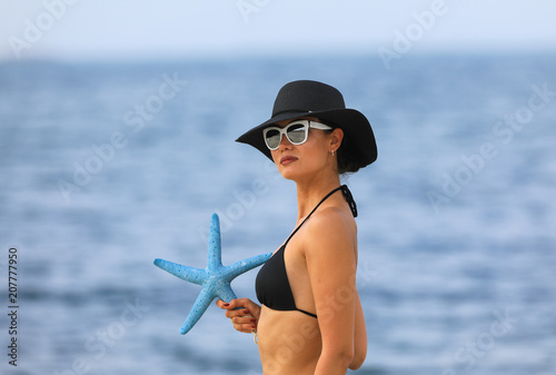 sensual sexy young girl holding a starfish on the beach