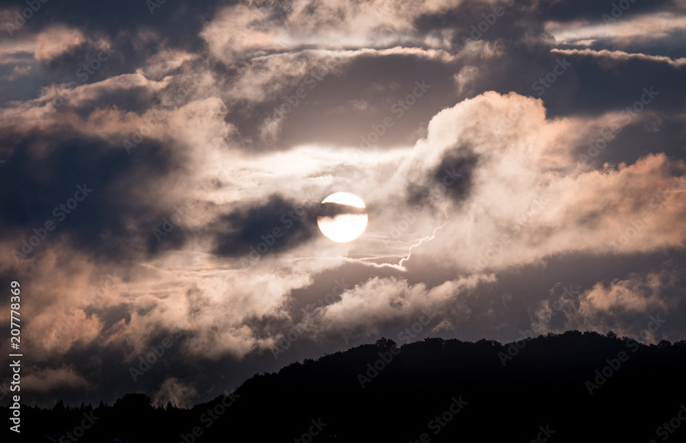 sun rise behind mountain into the clouds