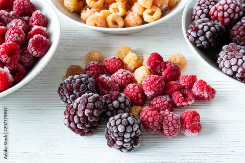 Fotografie frozen mixed berries on a white plate on a wooden white table