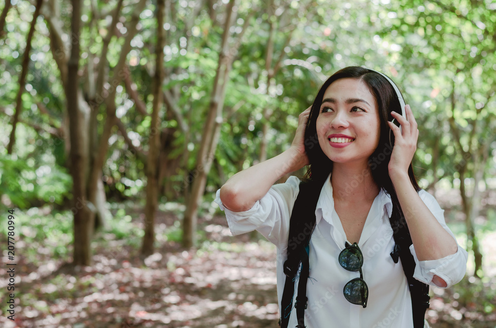attractive woman adventure hiker go to trekking in the forest sightseeing natural at holiday travel concept with headphone listening music. attractive woman adventure hiker go to trekking in the forest sightseeing natural at holiday travel concept with headphone listening music.