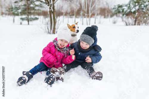Cute children and dog playing in snow.