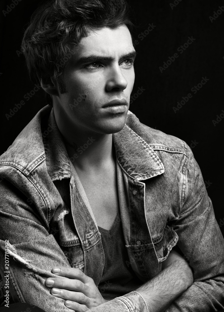 Obraz premium Black and white portrait of young handsome man on black background.