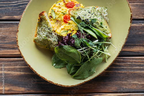 top view of vegetarian salad with spinach and sprouts on plate on wooden tabletop