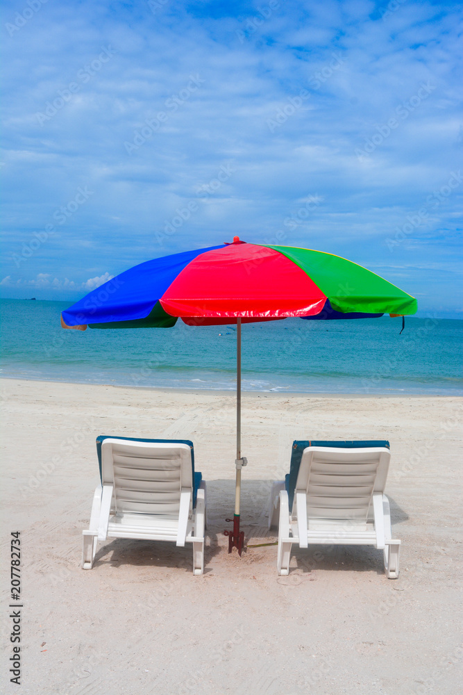Umbrella with chairs in beach background