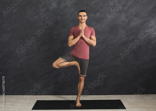 Young man training yoga in tree pose