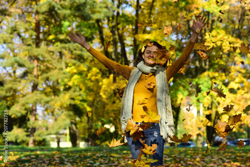 Autumn leaves falling on happy young woman