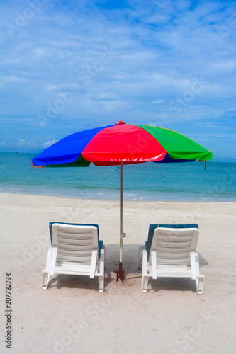 Umbrella with chairs in beach background