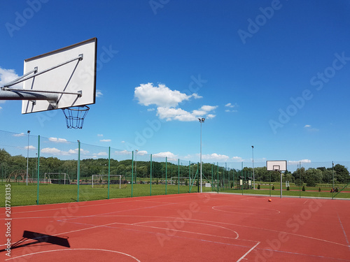 Modern basketball court under the open sky with artificial red coating. Location of team sports events. Physical education of citizens. Healthy lifestyle. Urban infrastructure for recreation, interest