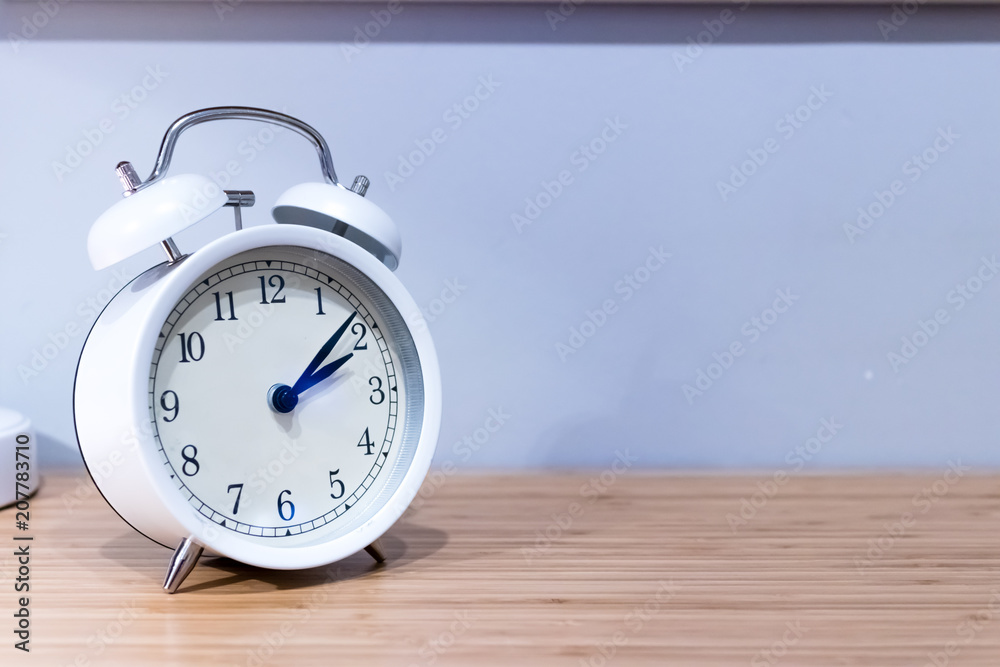 White alarm clock on wooden desk White alarm clock on wooden desk