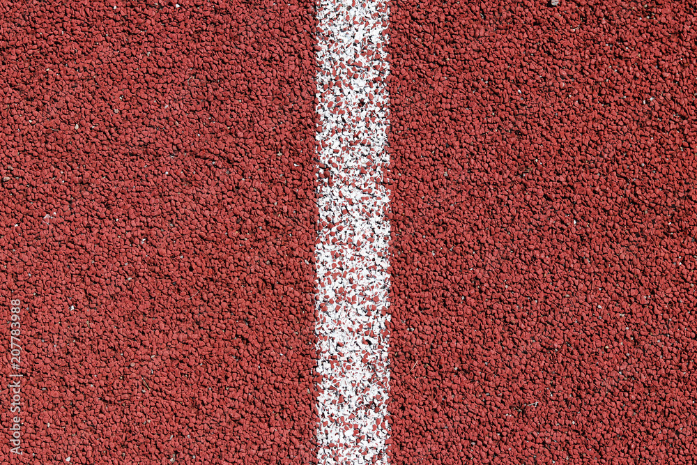White strip of markings on a red background of rubberized cover of sports grounds and stadiums for outdoor use. Red and white relief texture of the background. White strip of markings on a red background of rubberized cover of sports grounds and stadiums for outdoor use. Red and white relief texture of the background.
