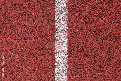 White strip of markings on a red background of rubberized cover of sports grounds and stadiums for outdoor use. Red and white relief texture of the background.