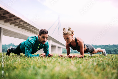 Couple doing plank exercise outdoors.