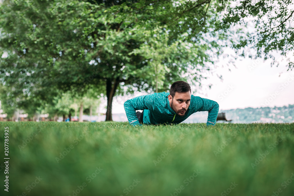 Young man doing push ups in the park.