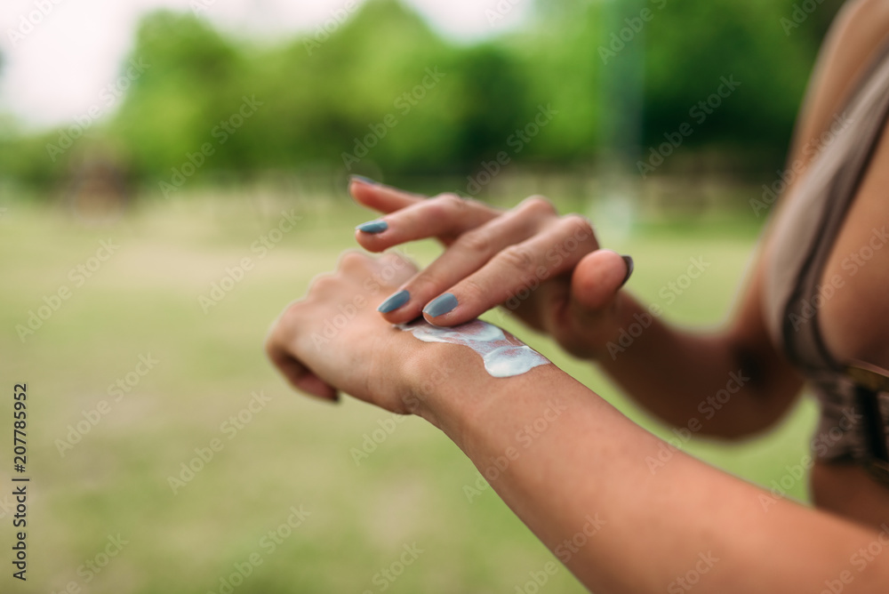 Close-up image of unrecognizable female person applying sunscreen creme.