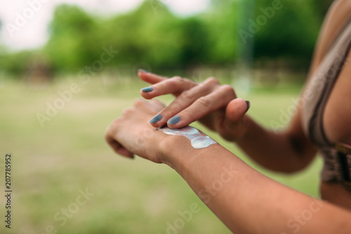 Close-up image of unrecognizable female person applying sunscreen creme. © bnenin