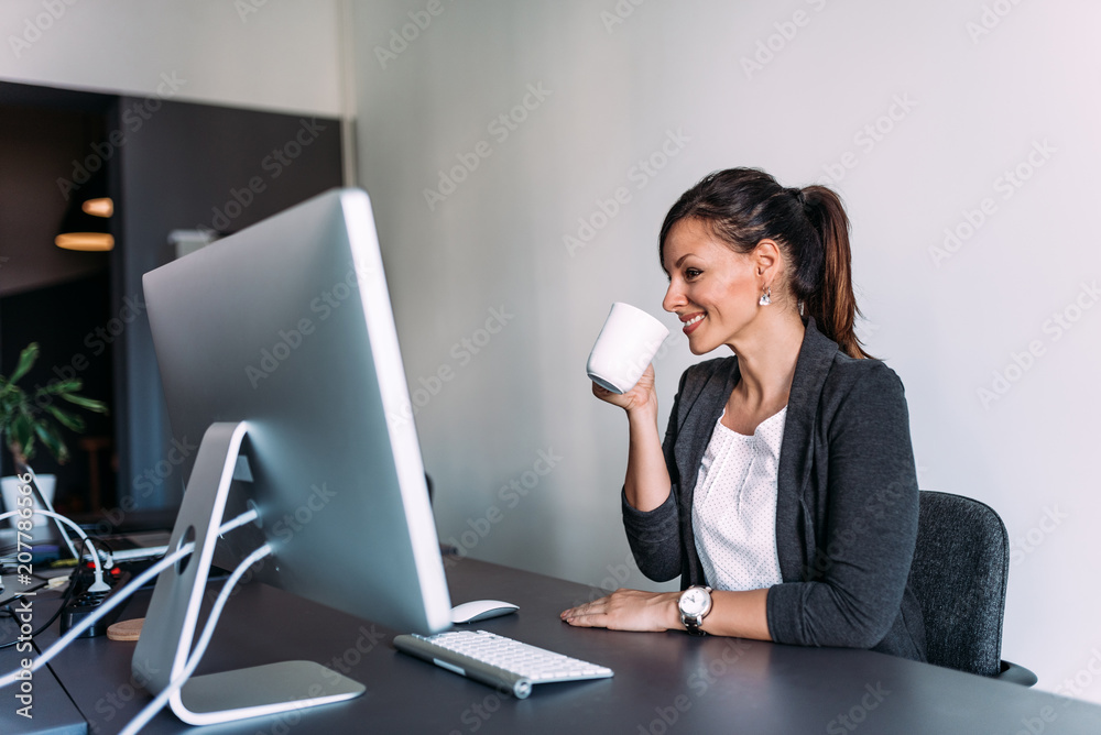 Attractive business manager sitting at office desk holding a cup. Attractive business manager sitting at office desk holding a cup.